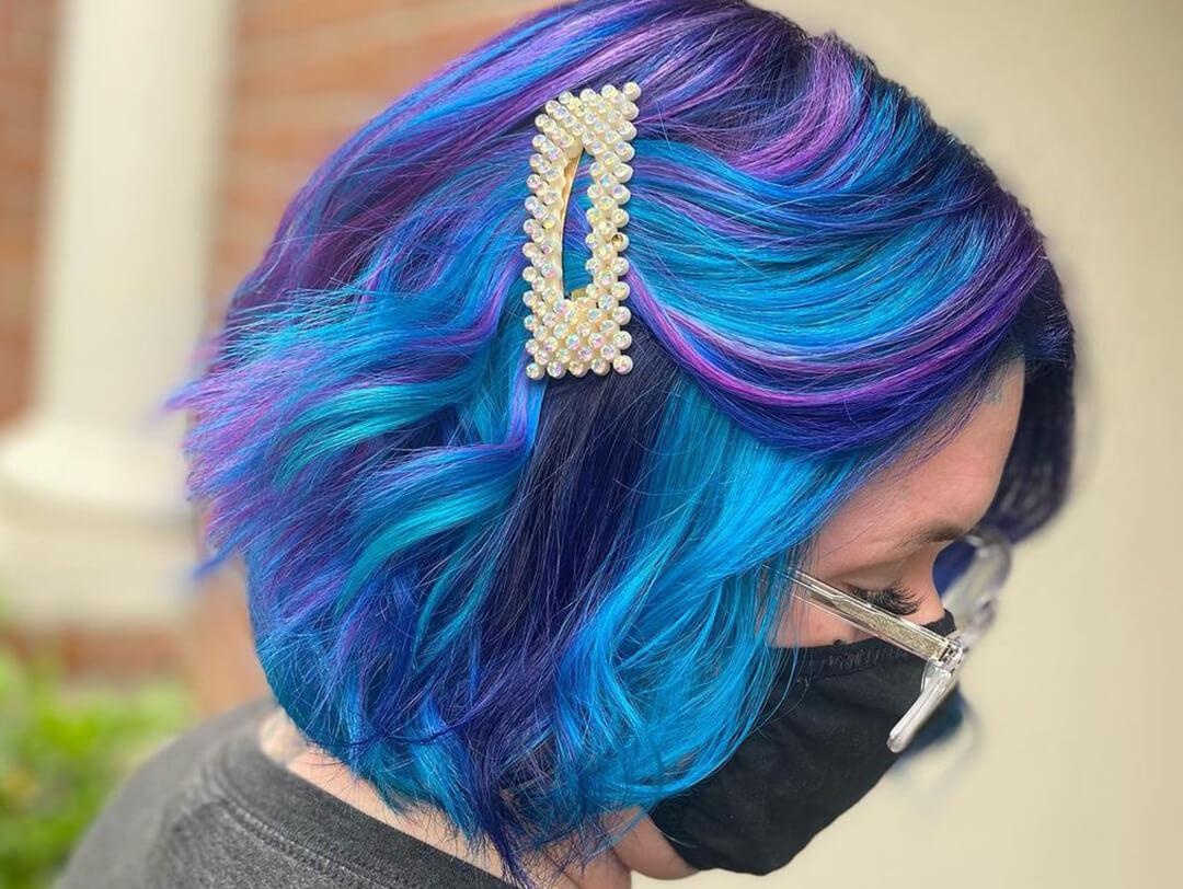 Close-up of a woman with face mask and eyeglasses rocking a galaxy-themed hair color Desktop
