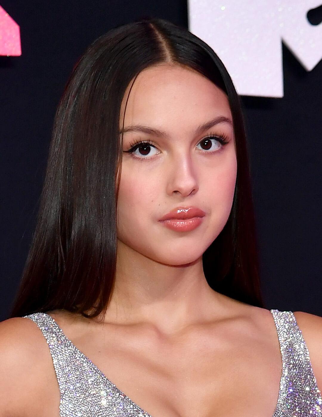 A photo of Olivia Rodrigo with her sleek straight-down hairstyle wearing a silver sequins against black background Desktop