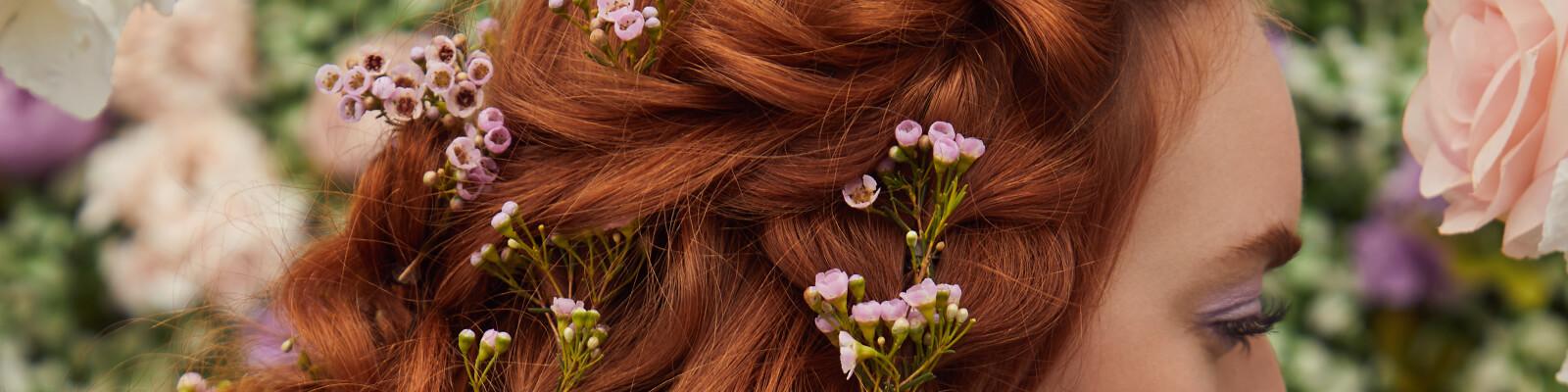 A close-up image of a model's braided red hair embellished with flowers Desktop