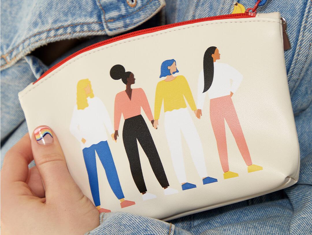 Image of a hand with colorful waves nail art holding the March 2021 IPSY Glam Bag against denim jacket Desktop