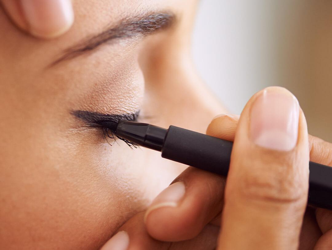 Close-up of a woman applying liquid eyeliner on her eyes Desktop