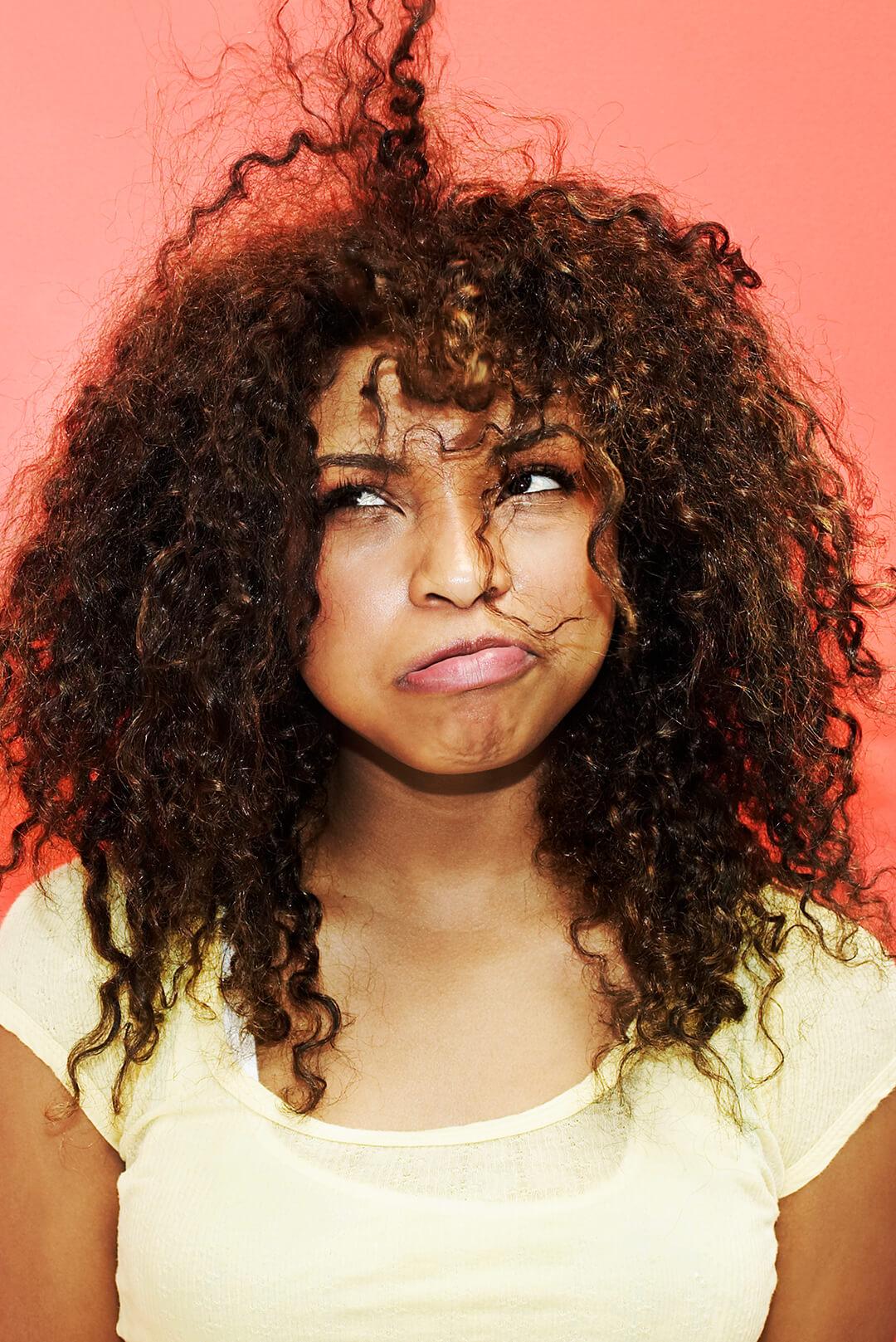 An image of a curly woman with static hair on a pink-orange gradient background Desktop
