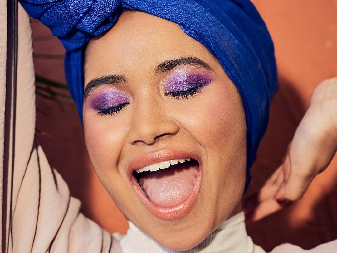 Close-up of a woman rocking a blue turban and bright purple eyeshadow look Desktop