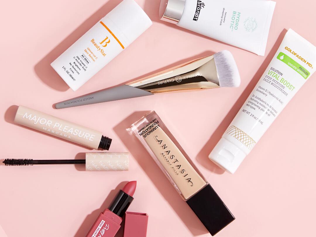 Image of skincare and makeup products and makeup brush scattered on pink background Desktop