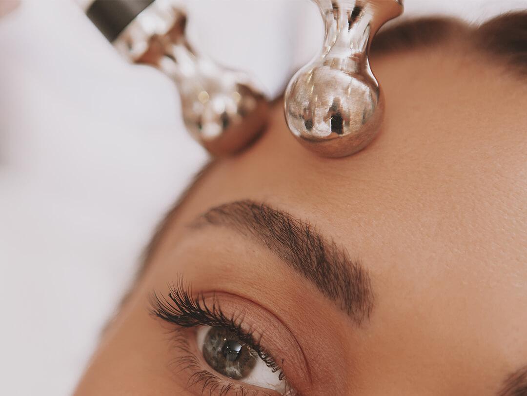 Close-up image of a woman getting a microcurrent facial treatment Desktop