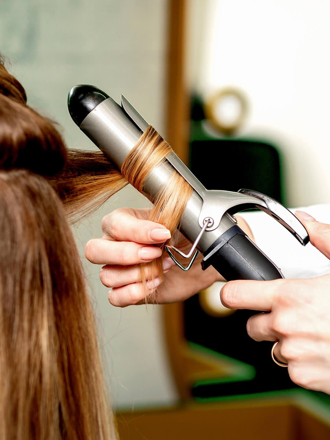 Hairstylist curling a woman's hair with a curling wand Desktop