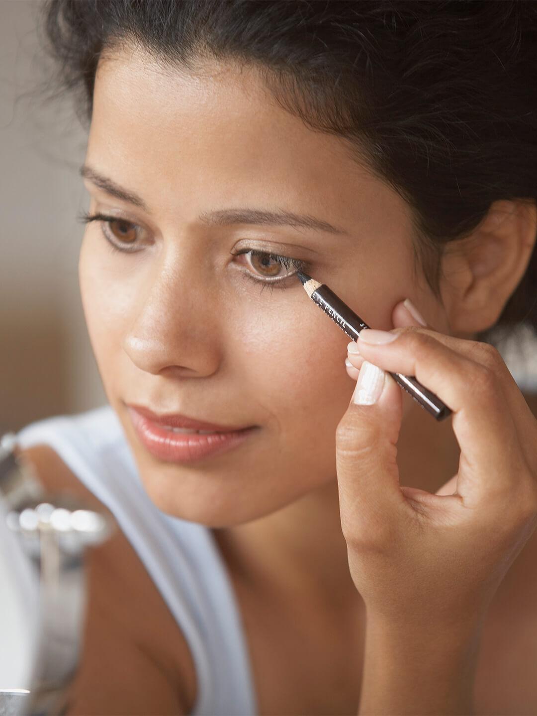 Image of a woman applying eyeliner while looking at herself in the mirror Desktop
