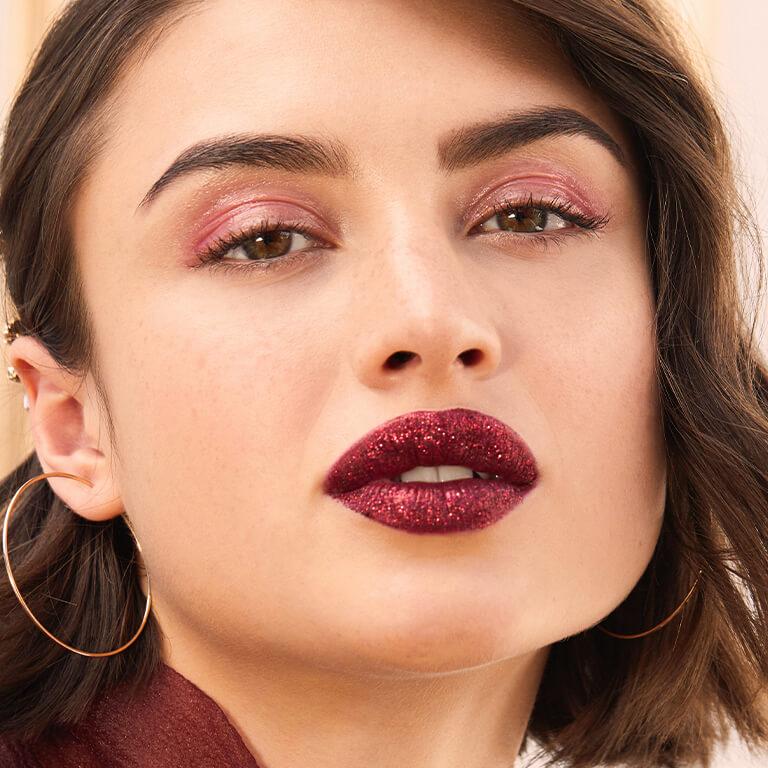 A closeup image of a model wearing shimmery pink eyeshadow and glittery berry lipstick and closeup image of model's lips with glittery berry lipstick Mobile