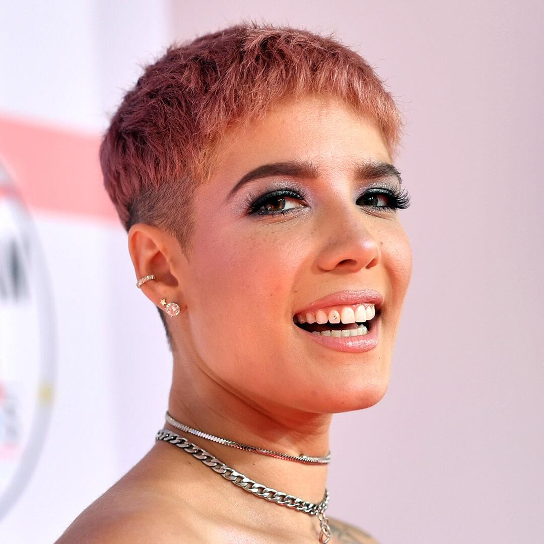 Close-up of a smiling Halsey rocking pink pixie cut hairstyle and pink eyeshadow makeup with bold lashes Mobile