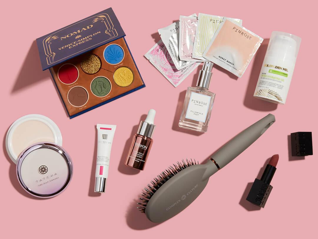 Makeup, skincare, hair care, and fragrance products and tools on pink background Desktop