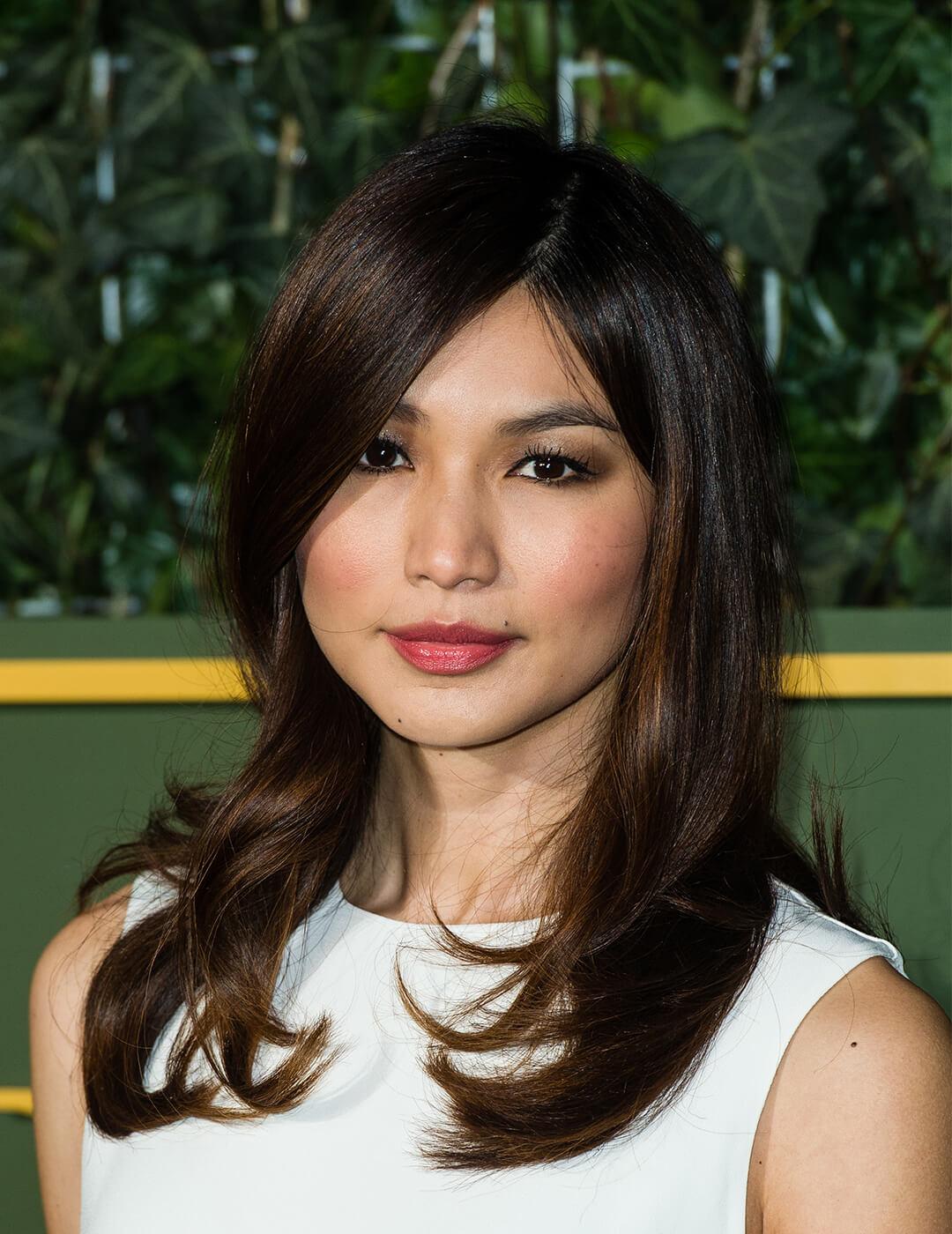 Close-up image of Gemma Chan rocking a neutral makeup look, white dress, and blowout hair Desktop
