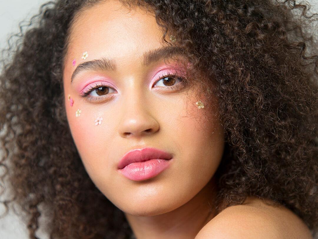 Close-up of a woman rocking a pink monochromatic makeup look and floral face stickers Desktop