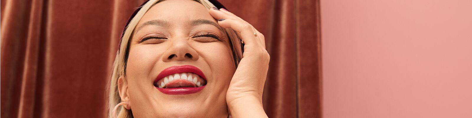 A model smiles at the camera with her tongue between her teeth. Desktop