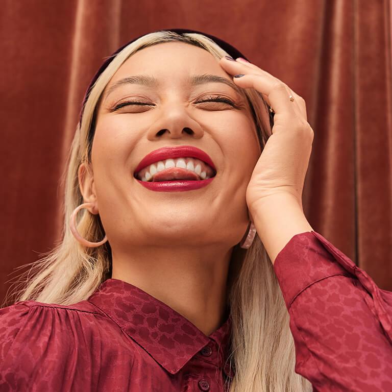 A model smiles at the camera with her tongue between her teeth. Mobile