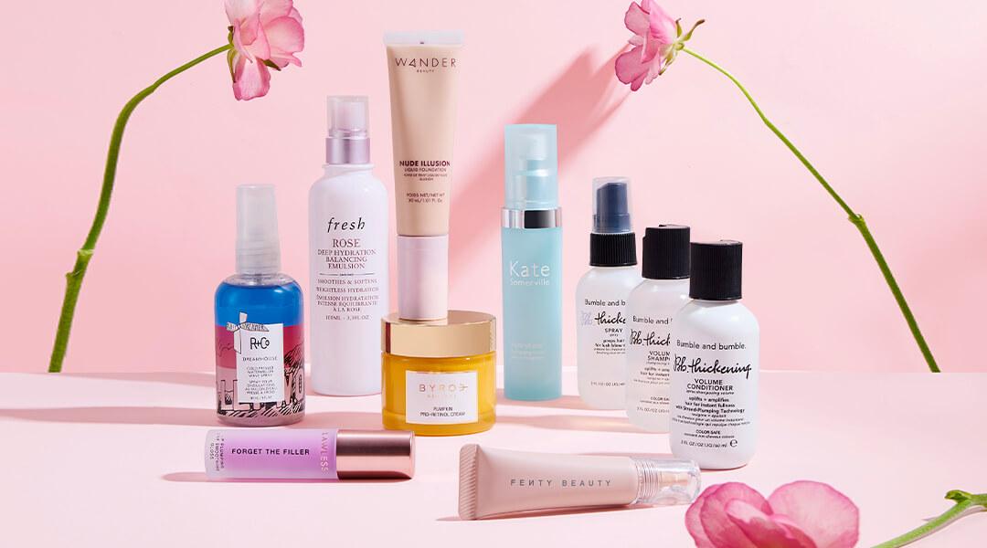 Skincare and makeup products from various brands scattered on pink background Desktop