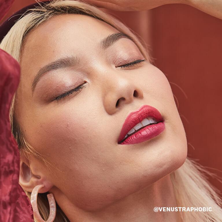 A closeup image of a model wearing champagne colored eyeshadow and bold rose lipstick Desktop