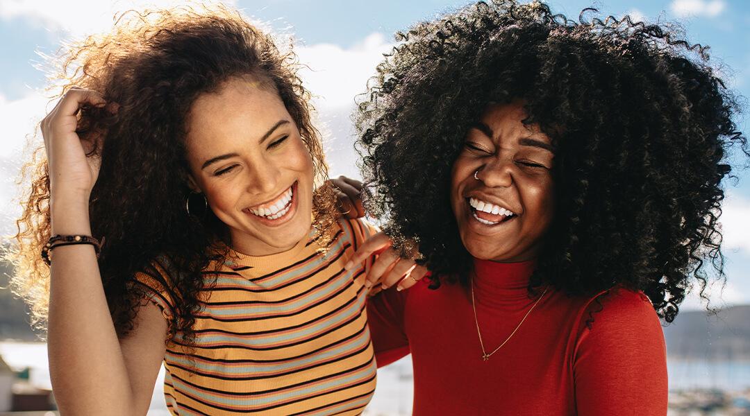Image of a two women laughing at the beach Desktop