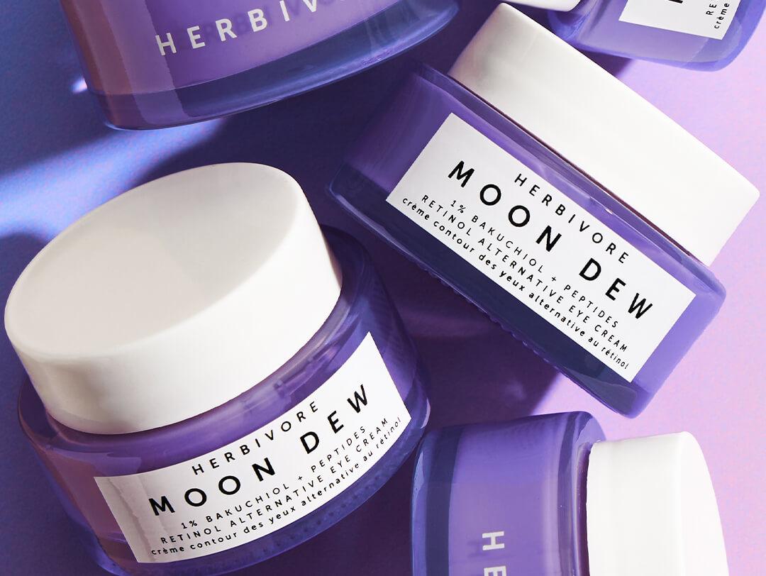 Jars of HERBIVORE BOTANICALS Moon Dew 1% Bakuchiol + Peptides Retinol Alternative Eye Cream on blue to purple ombre background Desktop