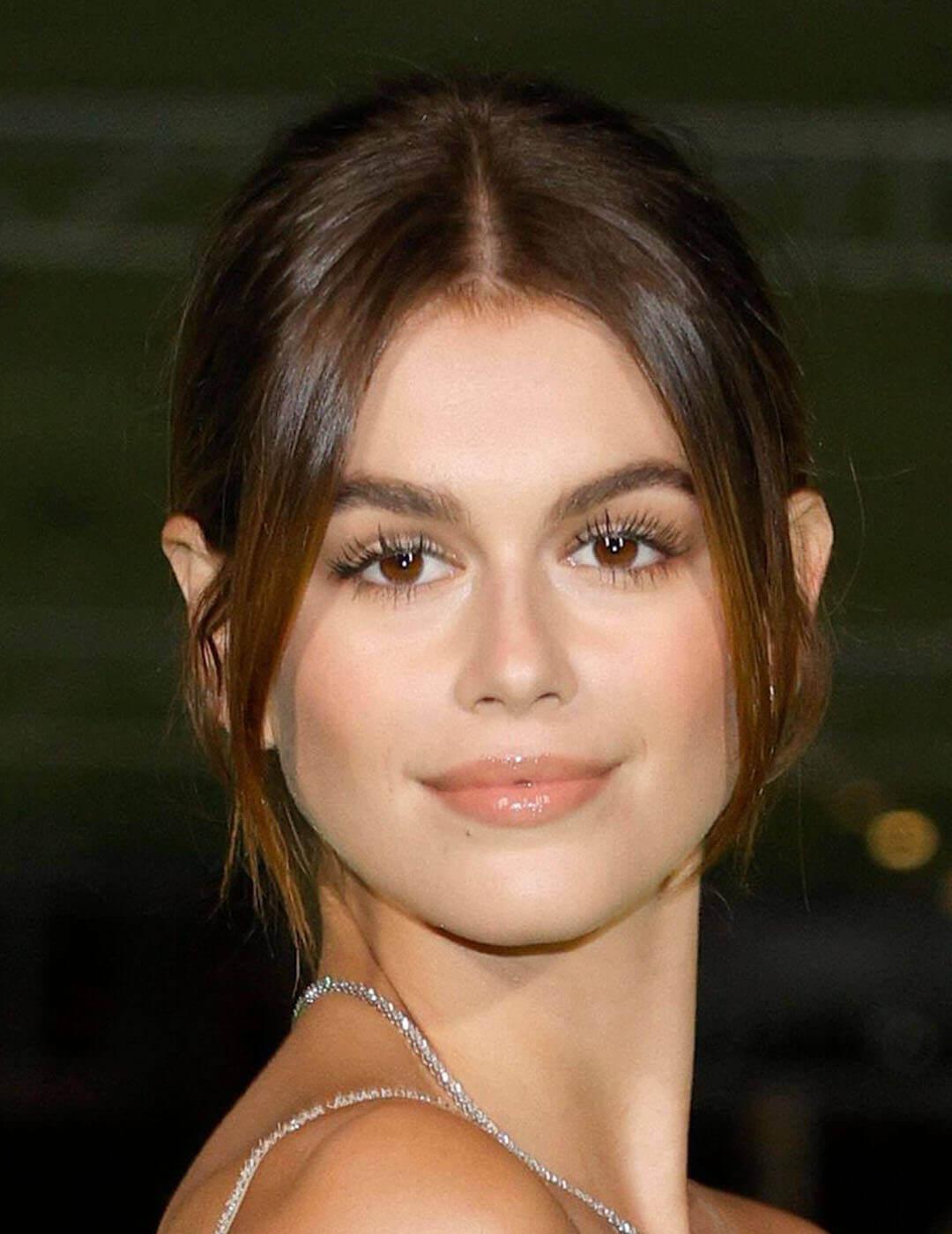 A photo of Kaia Gerber in her charming smile using a nude-colored lipstick in her updo hairstyle with two side bangs Desktop