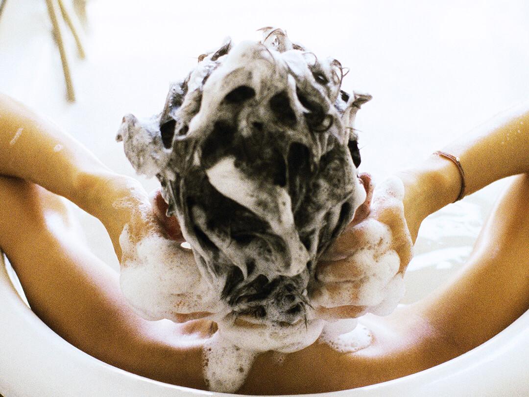 Woman in bathtub shampooing hair Desktop