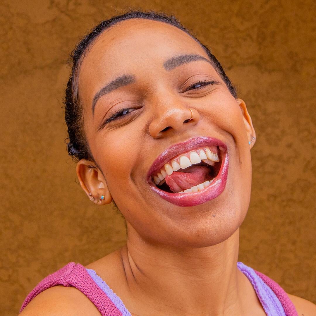 Close-up image of a smiling Bianca Alexa in a pink and purple top paired with a shimmery nude pink lipstick Desktop