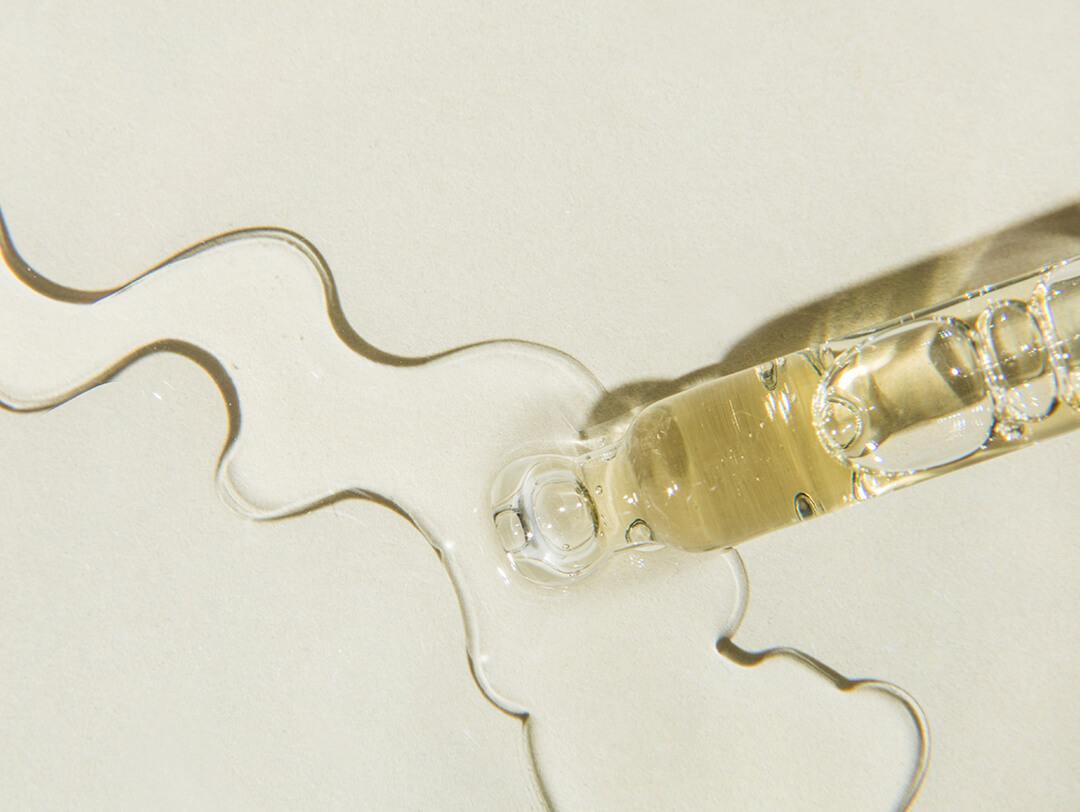 Liquid aromatic cosmetic oil drop with pipette on beige background Desktop