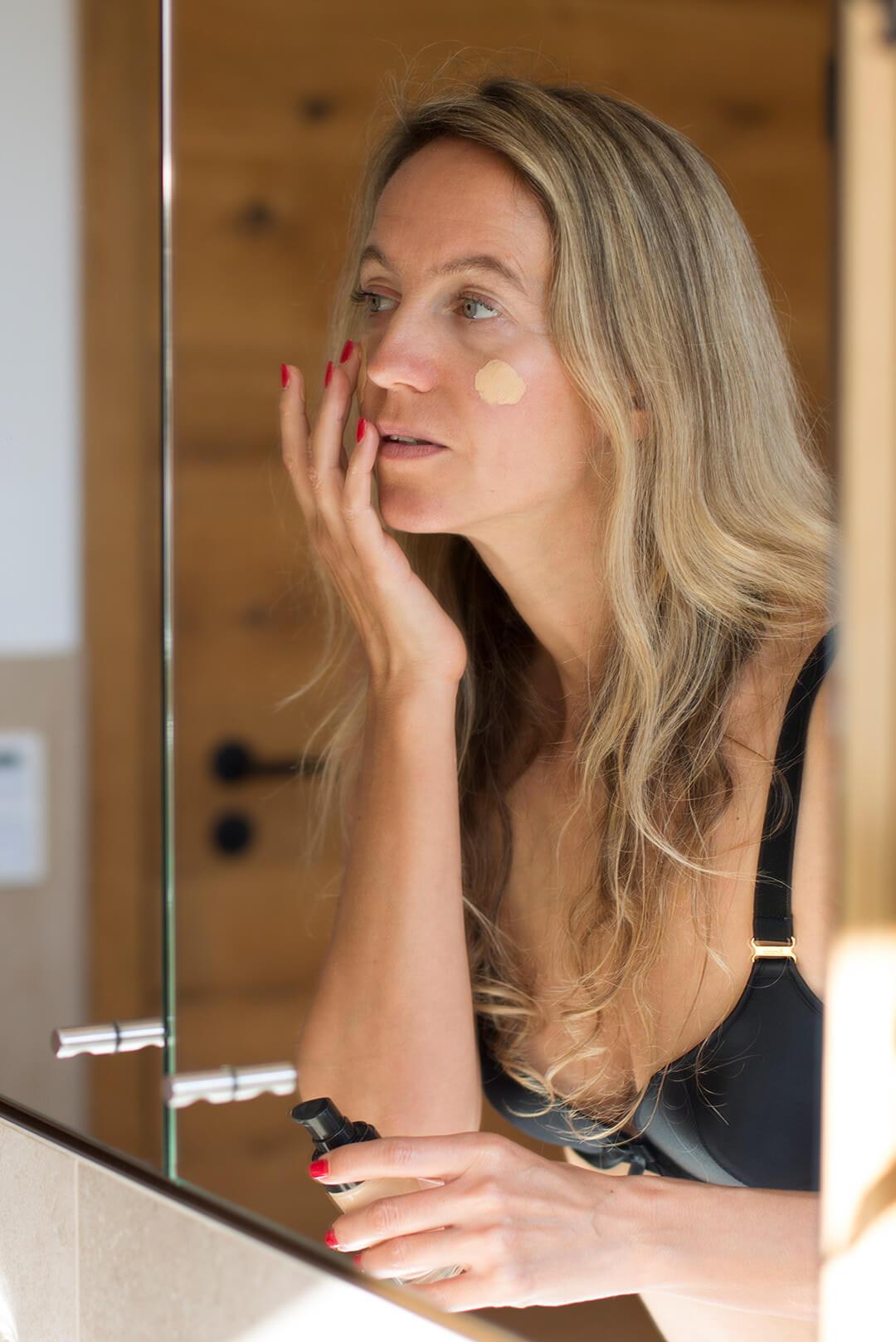 A photo of a model applying foundation in front of bathroom mirror Desktop