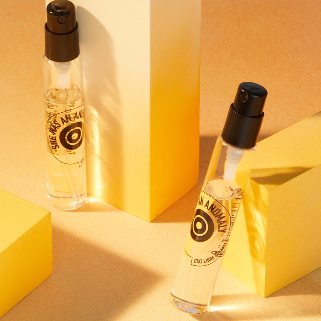 Two tubes of ETAT LIBRE D’ORANGE She Was An Anomaly against small yellow boxes on yellow background Desktop