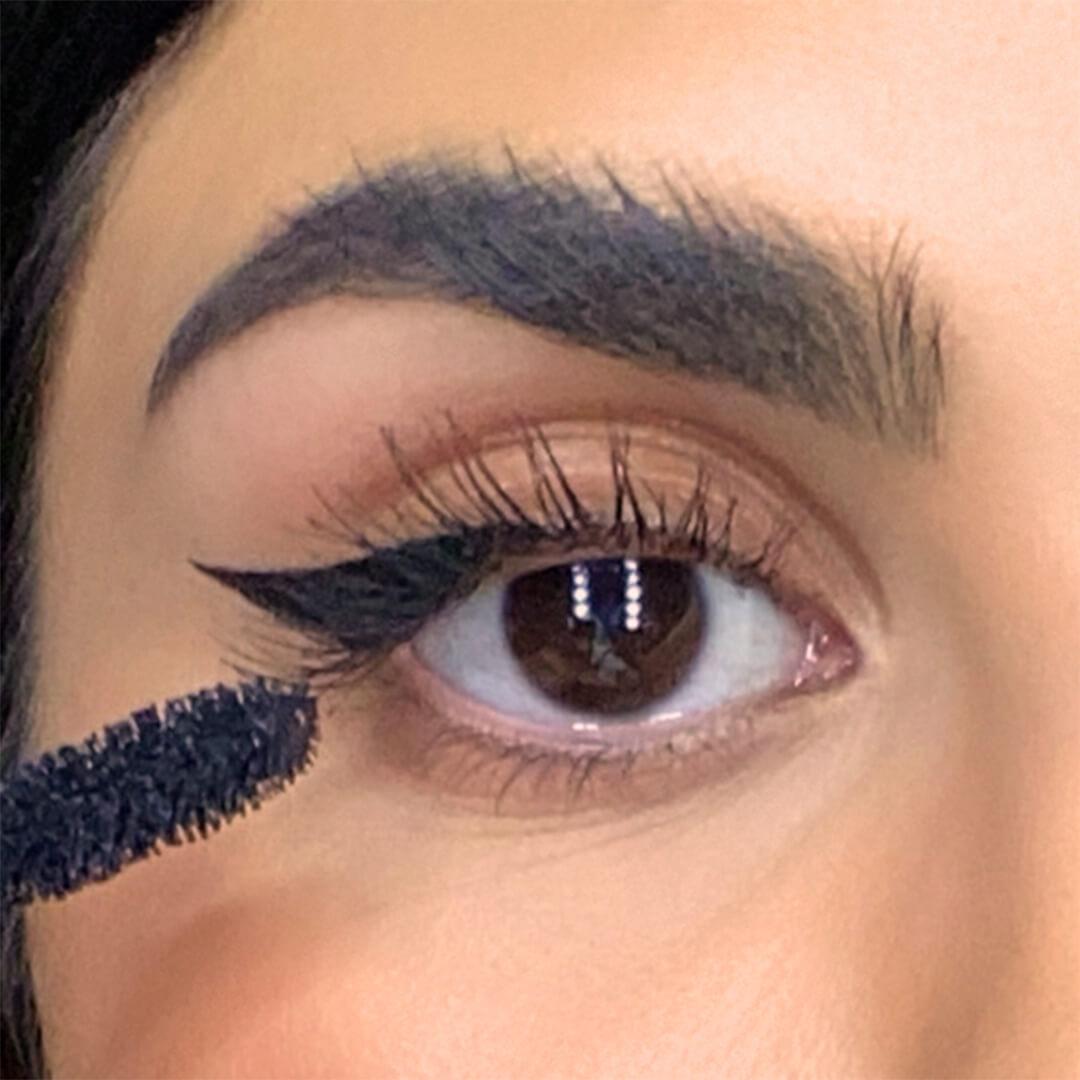 Close-up of a woman with cat eyeliner look applying mascara Mobile