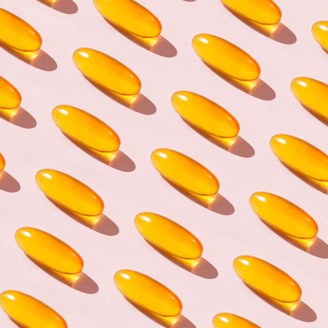 A photo of soft fish oil capsules on a pink background Desktop