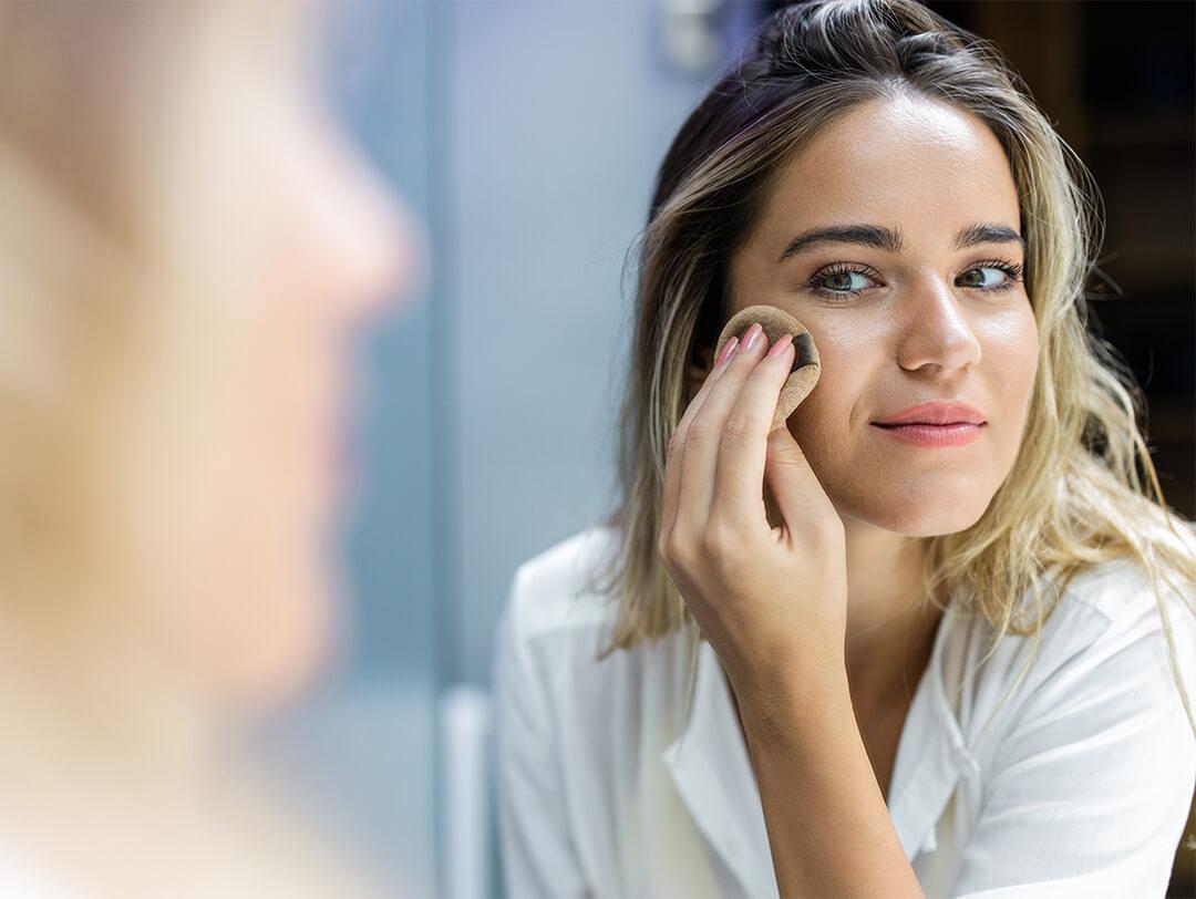 Image of a woman putting on face makeup while looking at herself in the mirror Desktop