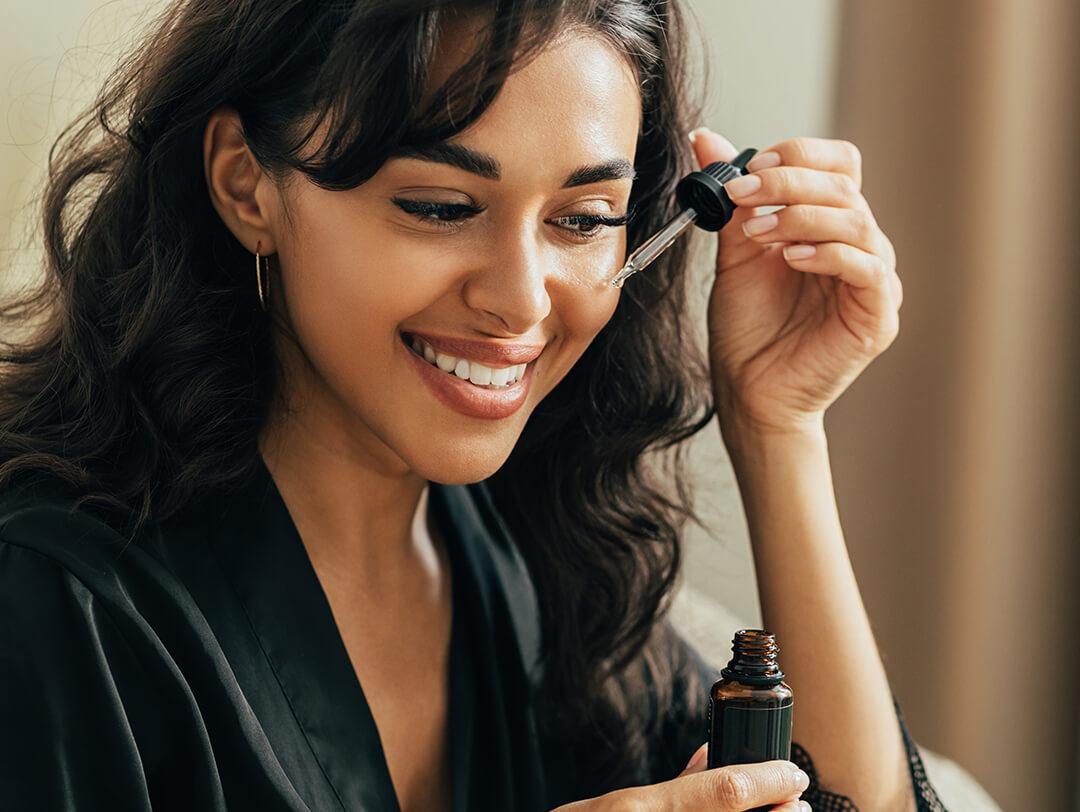 A closeup of a model applying face serum Desktop