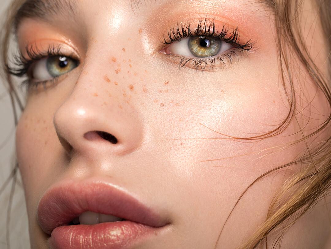 Closeup studio shot of a beautiful young woman with freckles skin posing against a grey background Desktop