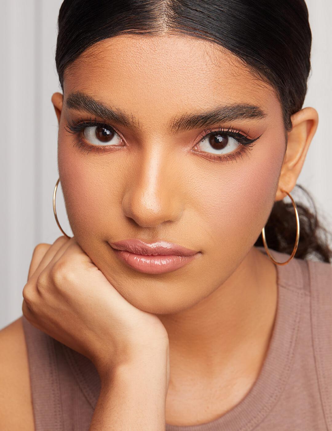 Close-up of a model with rose gold eyeshadow makeup look, nude pink lips, and gold hoop earrings Desktop
