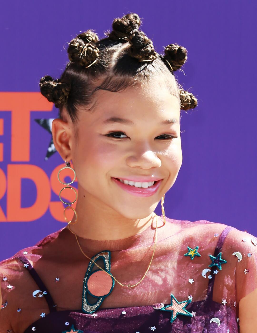 Close-up of a smiling Storm Reid looking cute in a outer space themed dress and bantu knots hairstyle Desktop