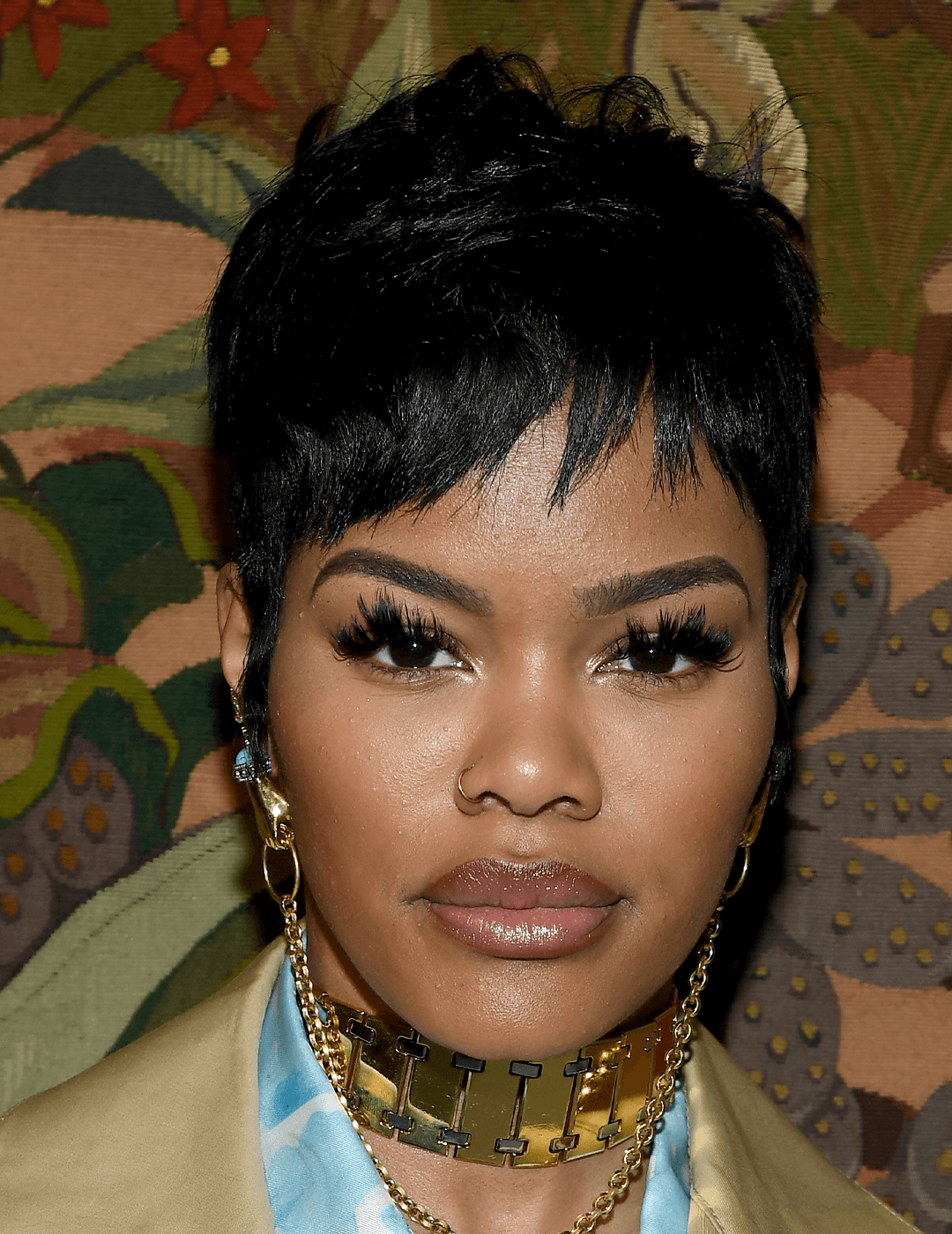 Teyana Taylor rocking a choppy pixie cut hairstyle, dangling gold earrings, gold chain choker, and neutral makeup look Desktop