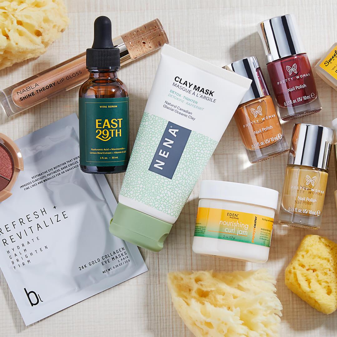 Skincare, makeup, hair care, and nail products on off-white textile with yellow sponges Desktop