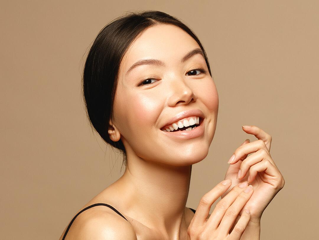 A photo of a smiling woman with healthy glowy skin Desktop