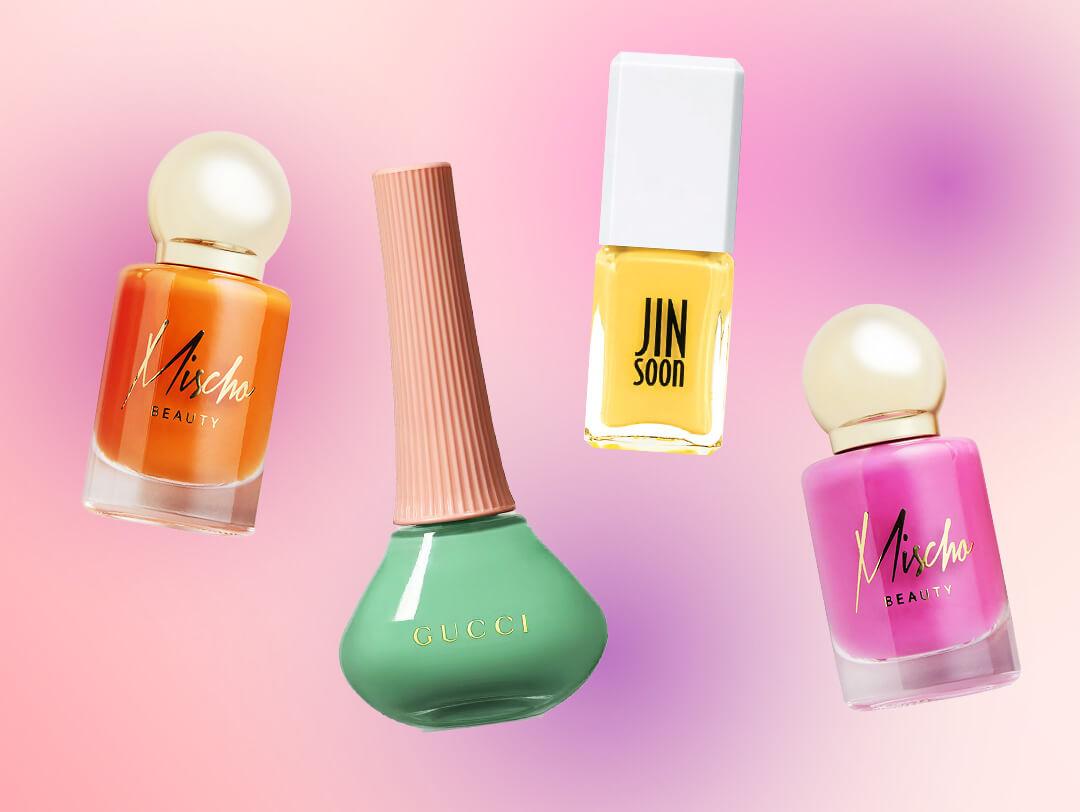 Four bottles of colorful nail polish from various brands on pink and purple ombre background Desktop