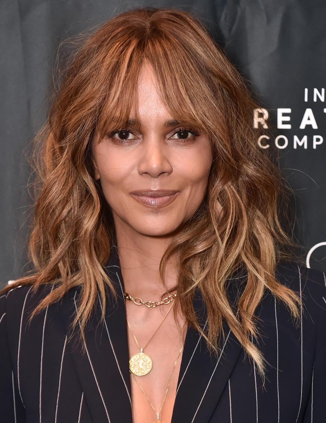 A photo of Halle Berry with a front feathering hairstyle with brown highlights wearing a black coat Mobile