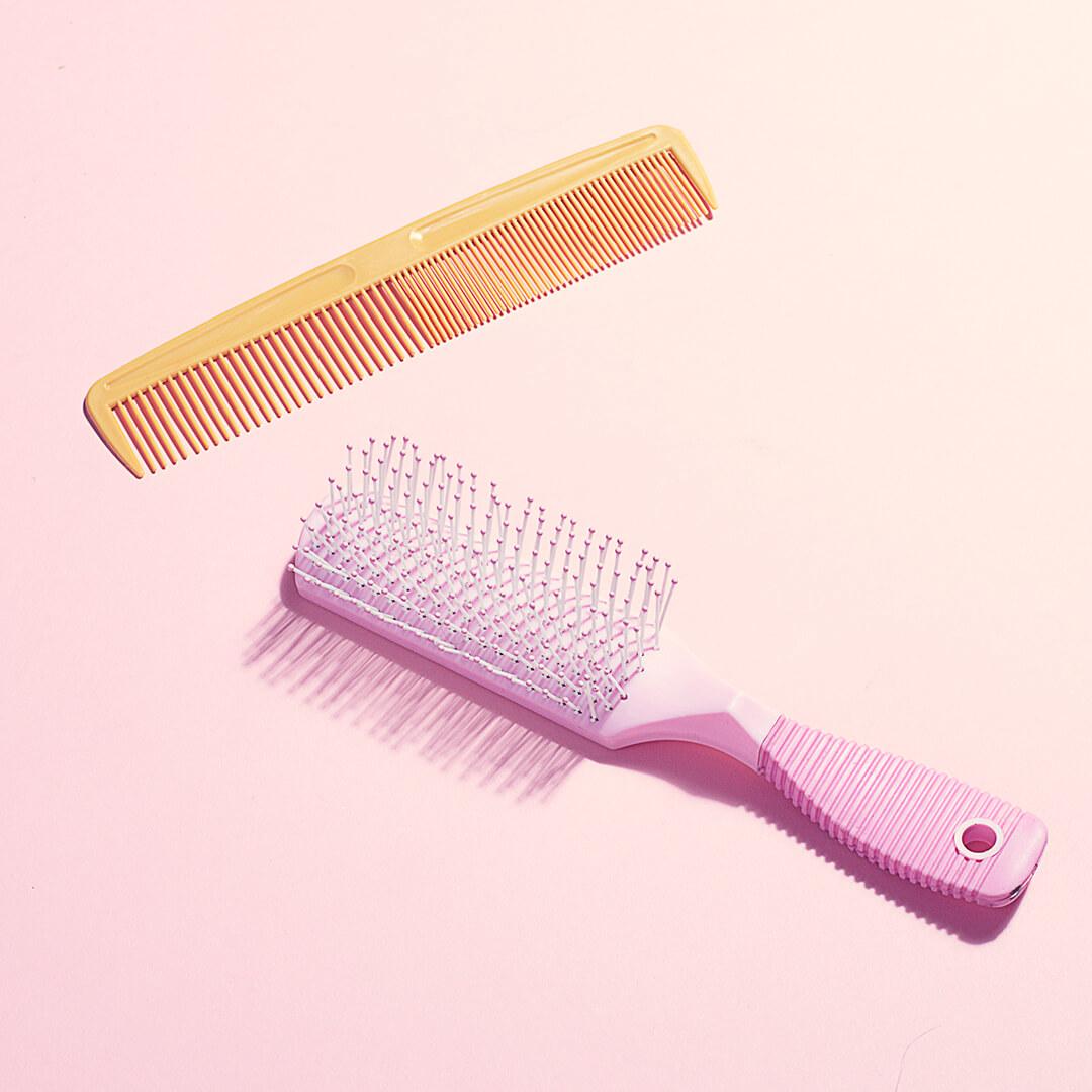 An image of a pink hair brush and a comb on a pink background. Desktop