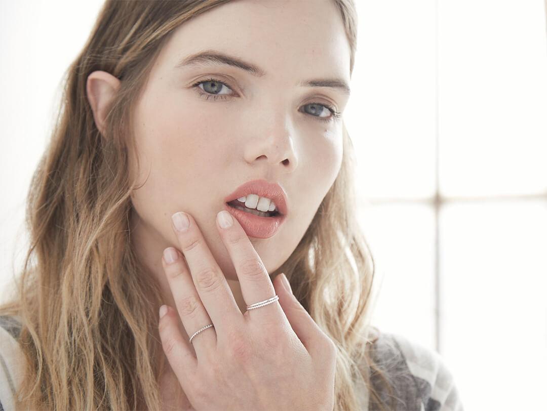 An image of a model gently touching her face. Desktop