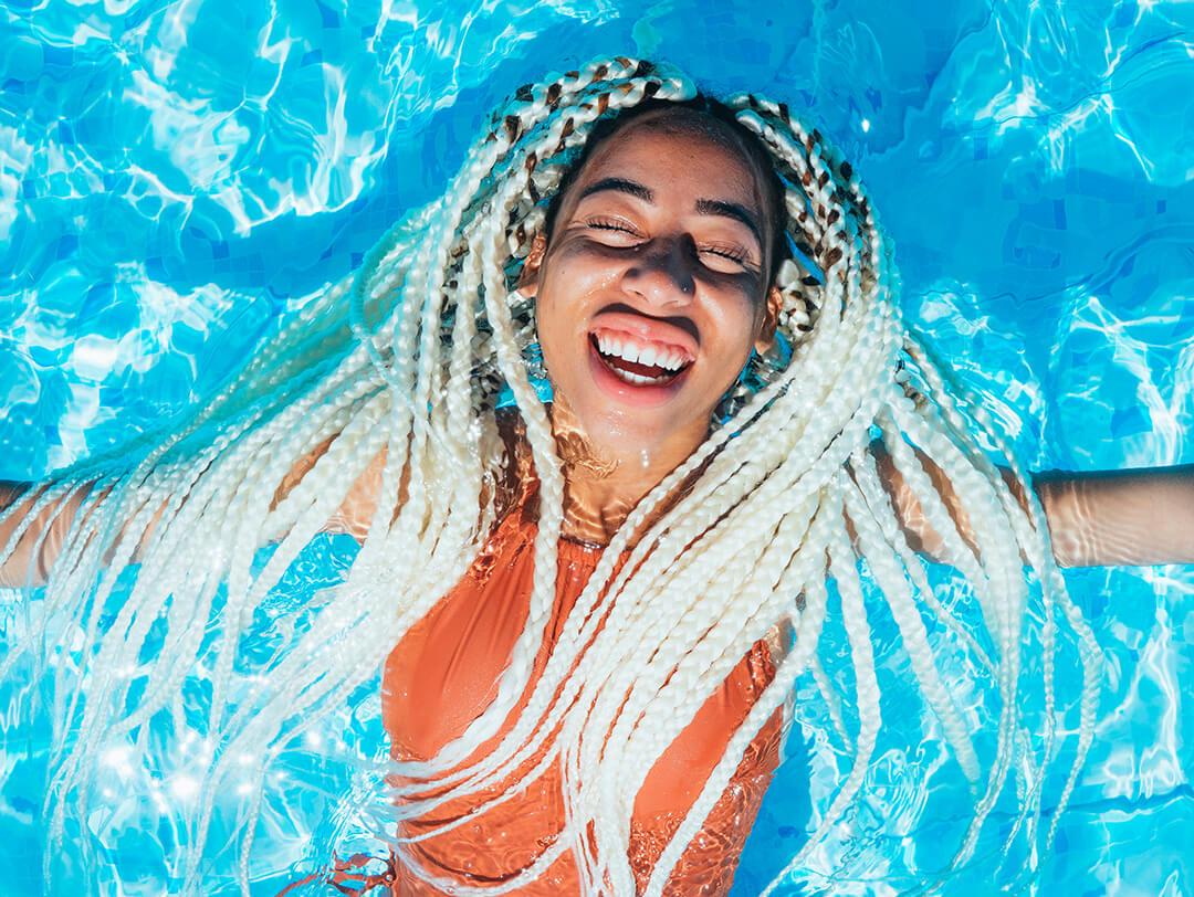 A photo of a model with blonde braided hair floating on the pool Desktop