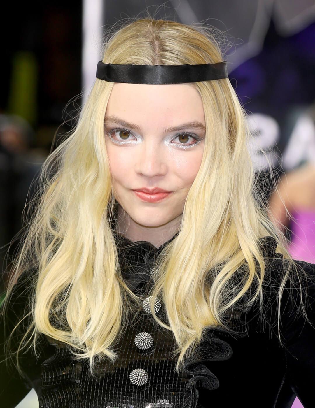 Anya Taylor-Joy rocking an inner eye highlights makeup look, black headband, and black dress with big buttons on the runway Mobile