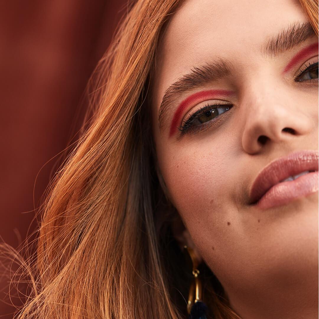 Close-up of a model rocking a vibrant red cut crease eye makeup look Mobile