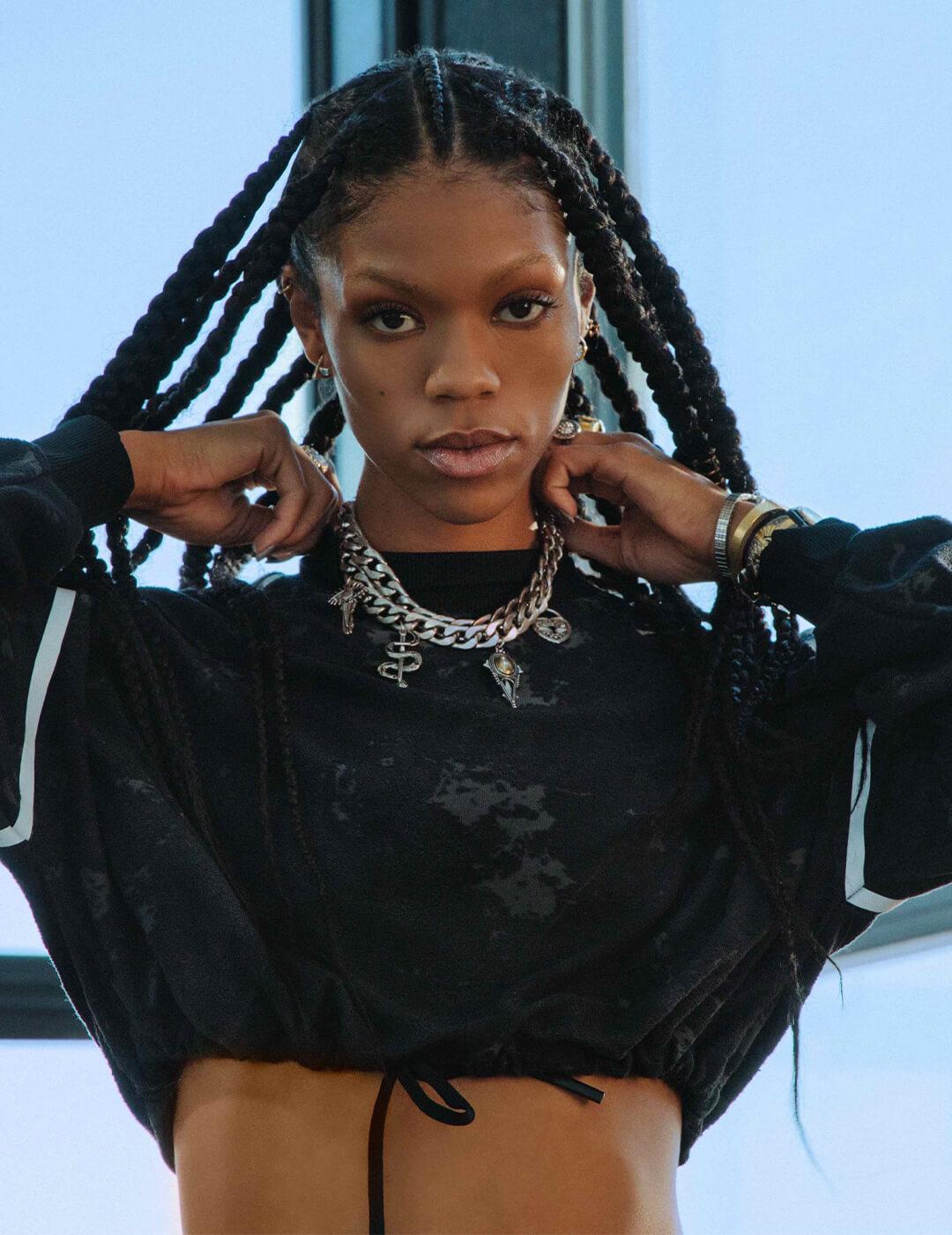 Vashti Cunningham looking fierce in a black cropped top, long box braids, and a silver necklace Desktop