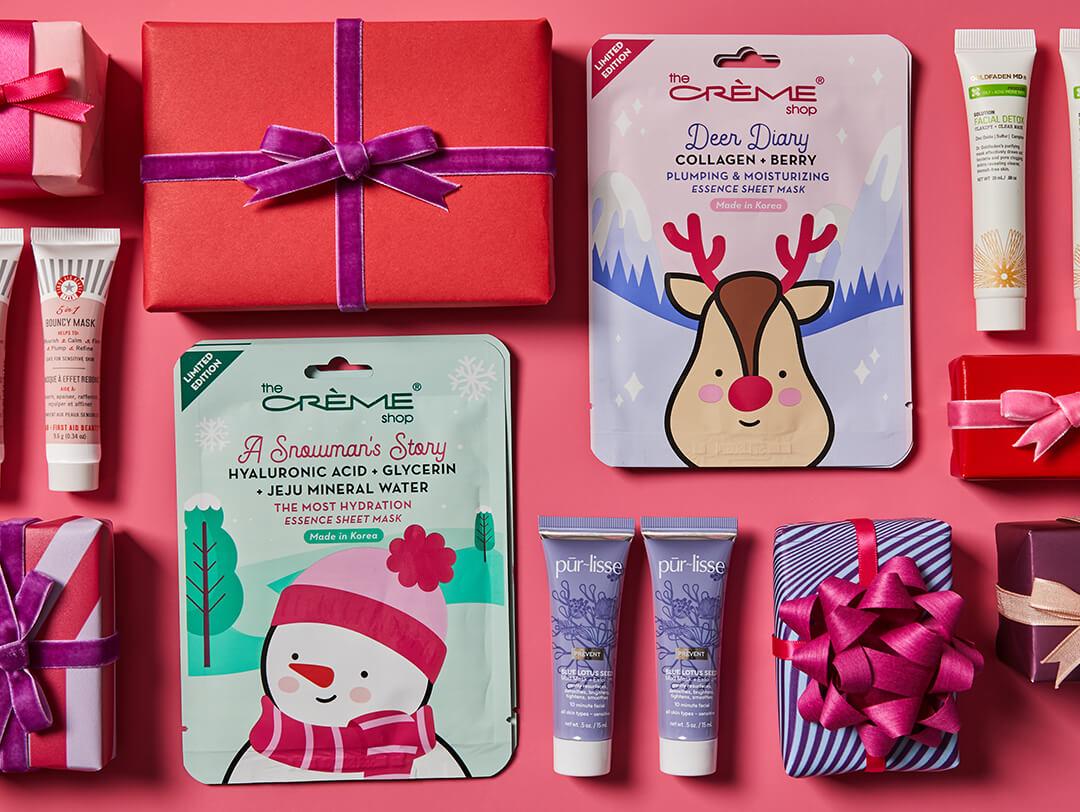 Flat lay image of different face masks from various brands and colorful gift boxes on pink background Desktop