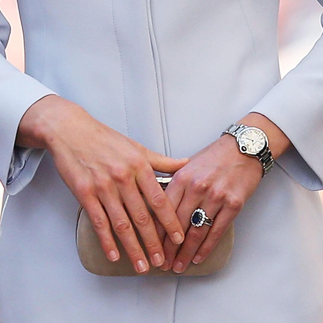 Close-up of Catherine, Duchess of Cambridge's hands with polished bare nails holding a light brown purse Mobile