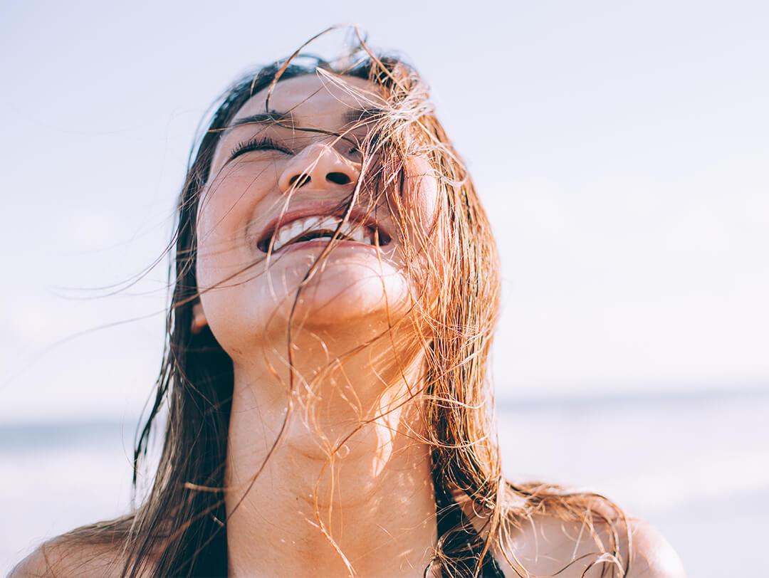 Image of a woman at the beach looking up and smiling Desktop