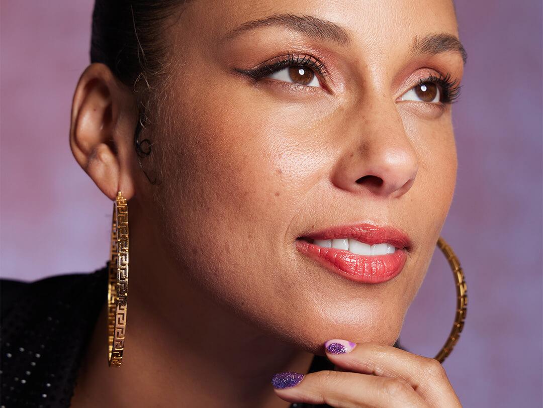 Close-up portrait of Alicia Keys rocking a natural makeup look against lilac background Desktop
